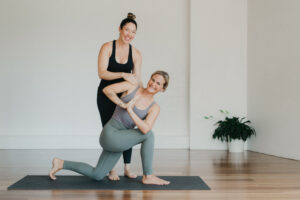 Yoga teacher assisting a student